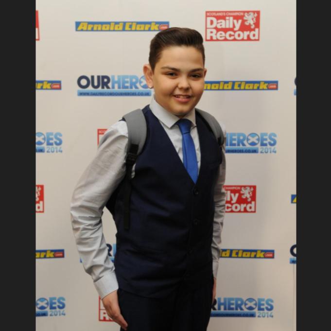 Sam in a suit standing in front of daily record signage